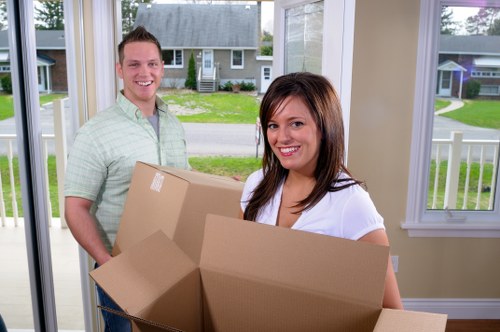 Local movers carrying boxes through an apartment hallway in Belmont